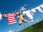 Baby Clothing and a teddybear on a clothesline towards blue sky